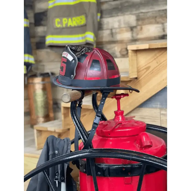 Red firefighter’s helmet on fire extinguisher with smooth leather chin straps