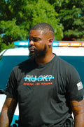 Person in a black stigma-breaking unisex tee with RUOK text and American flag patch