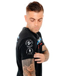 Black polo shirt with logo patches showcasing a tattoo, promoting stigma-breaking unisex tee