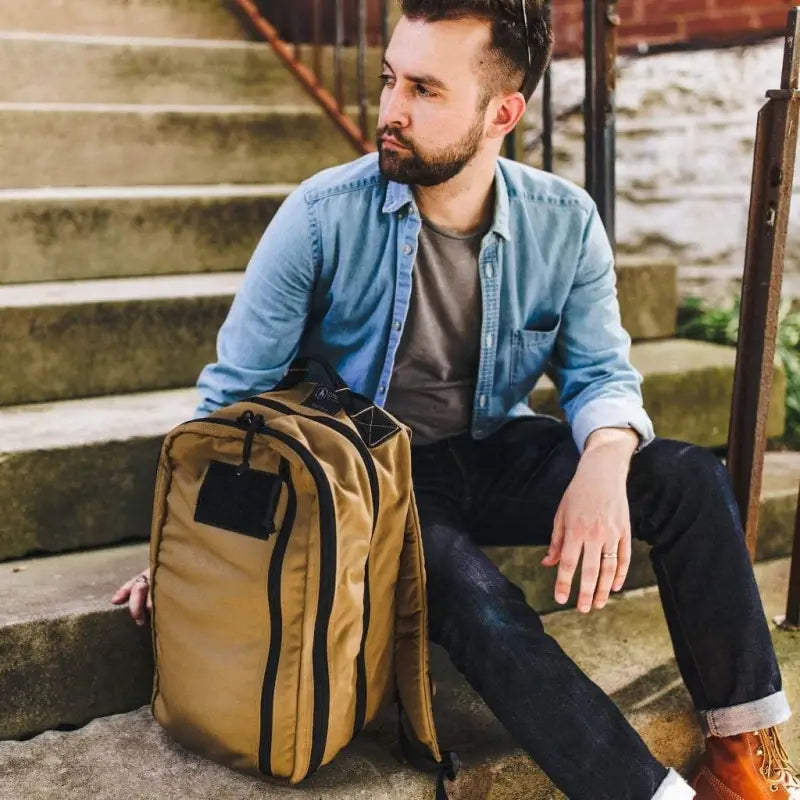 Tan canvas backpack with black accents on steps, featuring 12HR Plus Royal Blue design