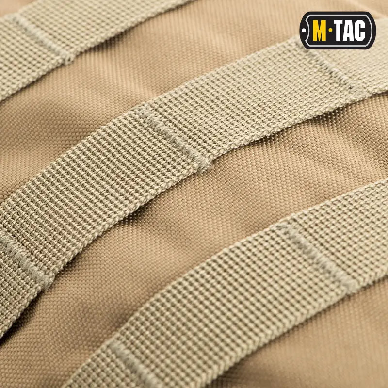 Tan tactical webbing straps on beige fabric of M-Tac Assault Pack with logo