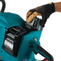 Teal Makita GEC01PL4 80V cordless chainsaw with electric brake and battery in use