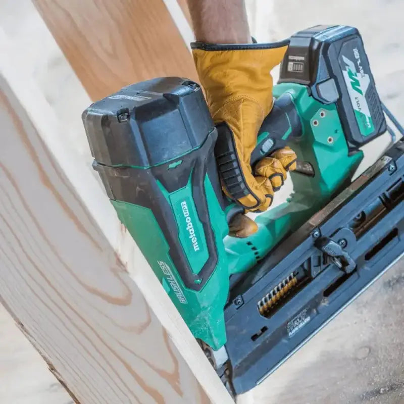 Teal-colored Metabo HPT 372121M cordless nail gun with battery in use by gloved hand