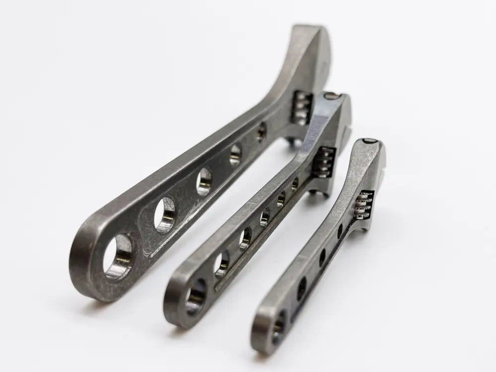 Three metallic adjustable wrenches in a row, showcasing the Wrench - Titanium NSN Pending