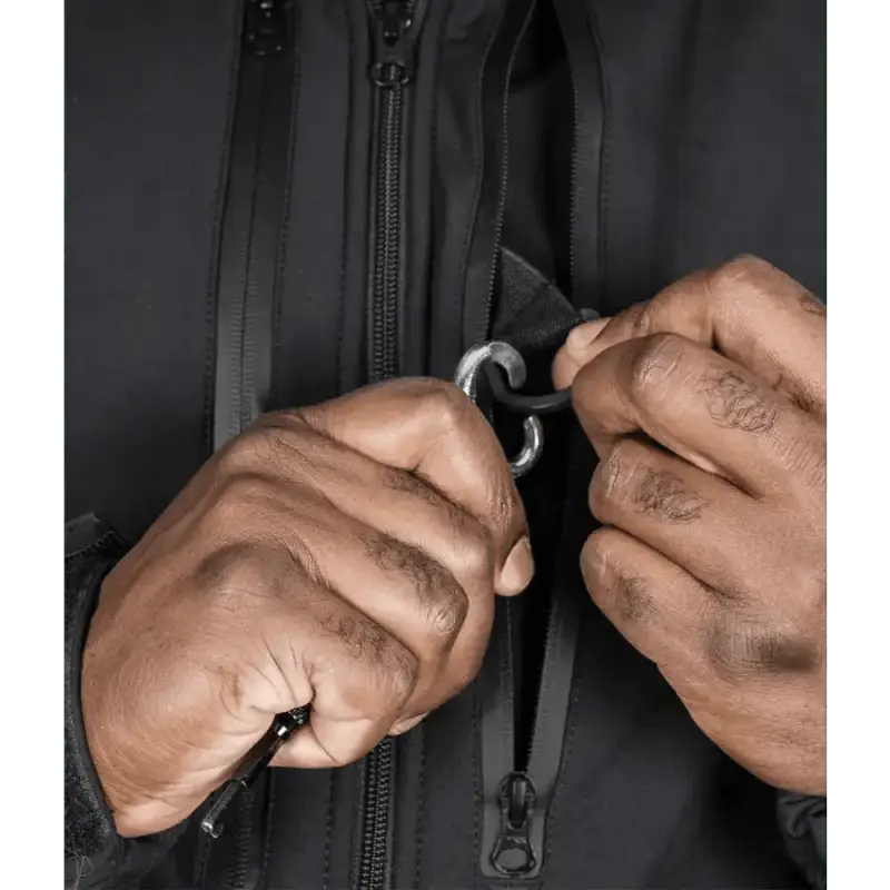 Hands zipping up the black zipper of a Tradecraft Tactical Jacket with body armor panel