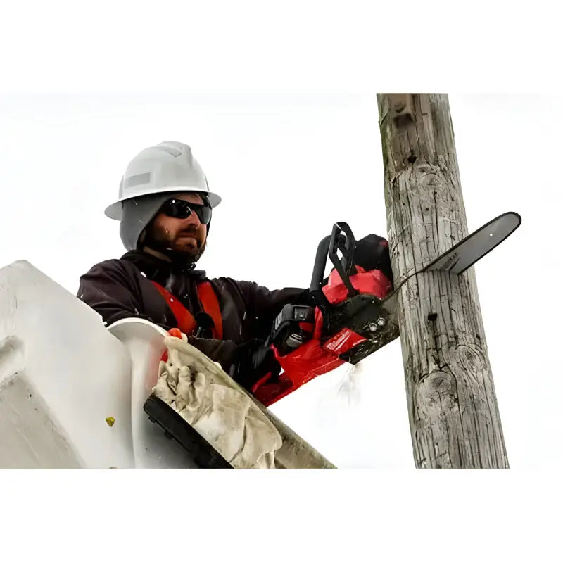 Utility worker in safety gear using Milwaukee 2727-20C M18 FUEL™ 14’’ Chainsaw near a pole