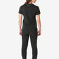 Back view of model in a Women’s Tuckable One-Pocket Scrub Top, joggers, and sneakers