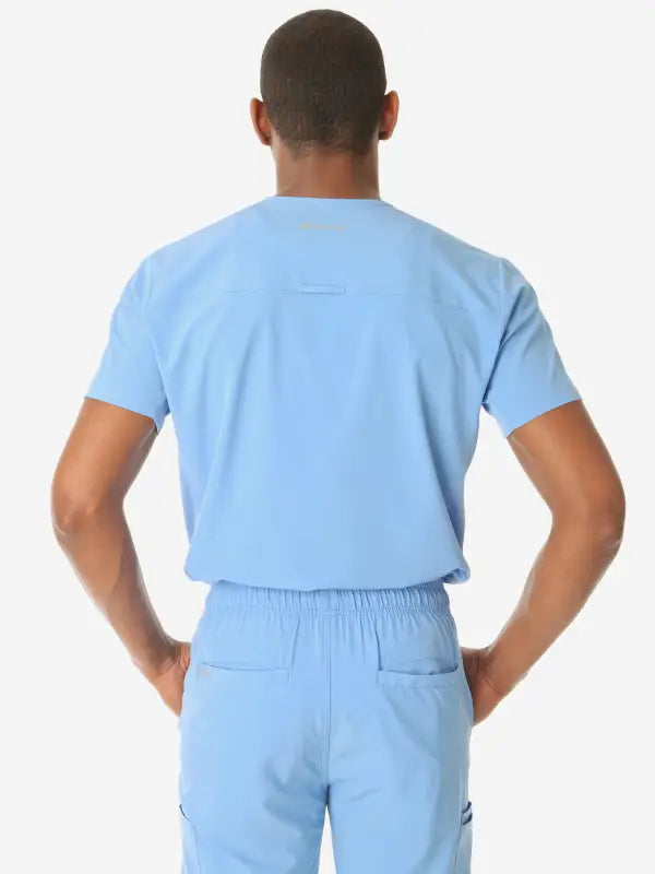 Back view of man in light blue men’s double-pocket scrub top showcasing its design