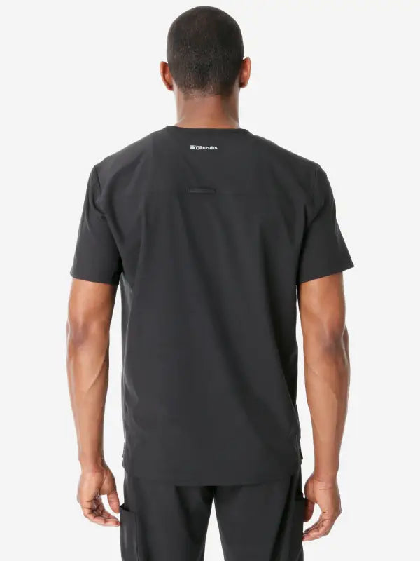 Back view of a plain black Men’s Double-Pocket Scrub Top with a logo near the neckline