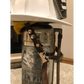 Vintage metal fire extinguisher with mounting bracket and leather chin straps displayed
