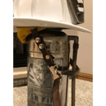 Vintage metal fire extinguisher with mounting bracket and leather chin straps displayed