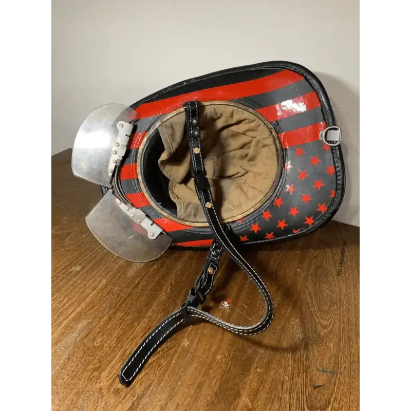 Vintage motorcycle helmet with red and black star pattern and smooth leather chin strap