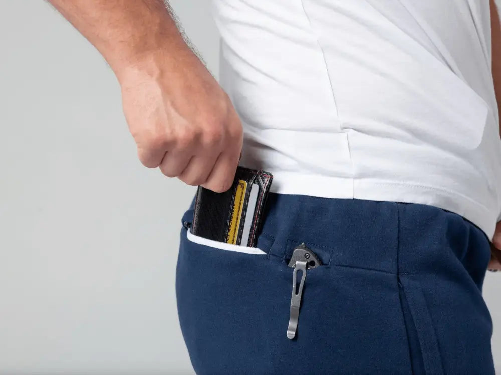 Wallet being removed from blue pants pocket of Carrier Joggers Mk.II with patented carrier retention