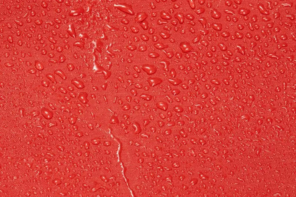 Water droplets on a red surface of a Firefighter Turnout Gear Bag with water resistant outer fabric