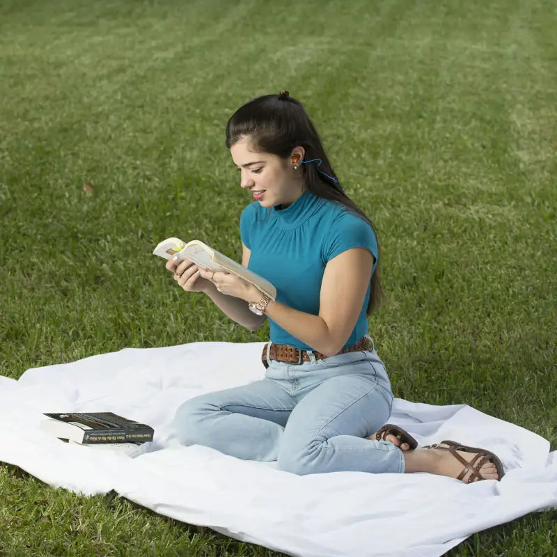 Woman reading a book while using 32dB NRR Soft Foam Earplugs with PVC Cord