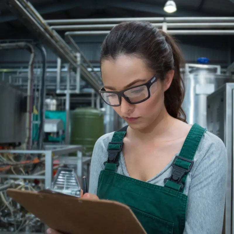 Woman in overalls using bifocal safety reader glasses for high impact protection