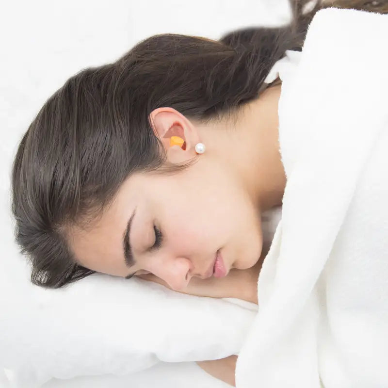 Sleeping woman with earplugs next to an earplug dispenser station with 250 pairs 32dB NRR