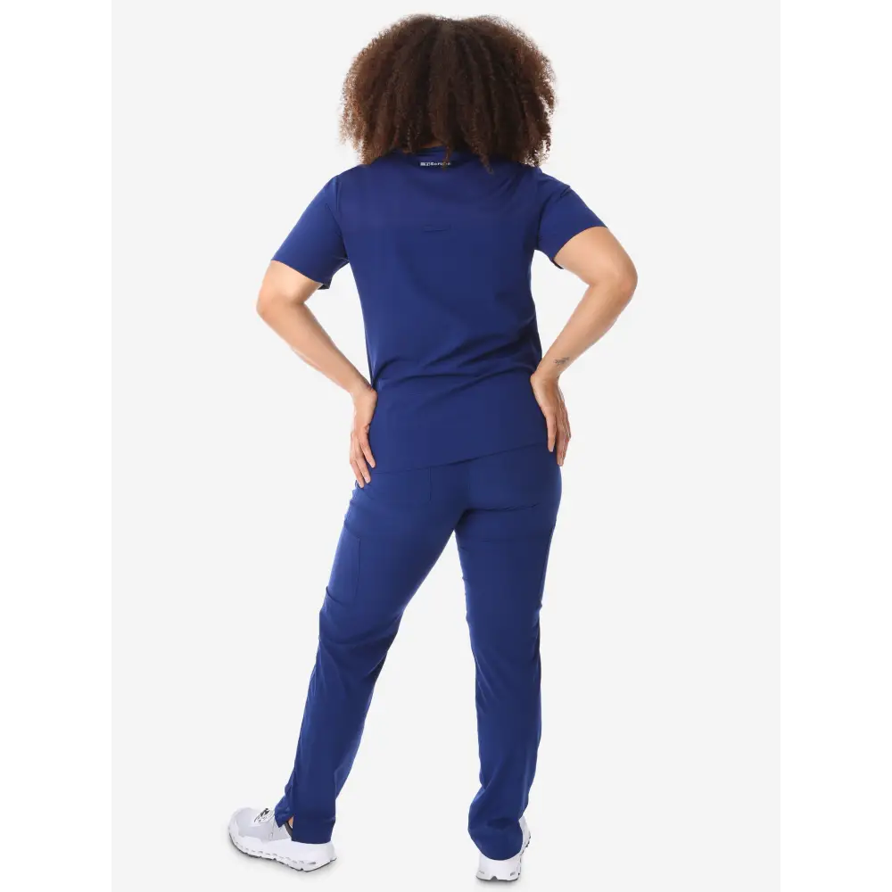 Navy blue women’s four-pocket scrub uniform with white sneakers for healthcare professionals