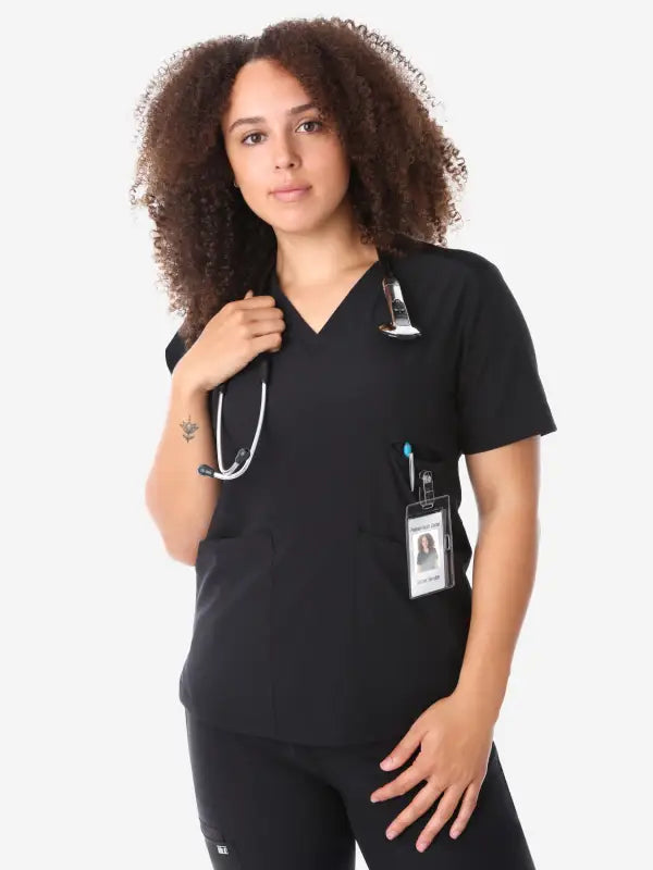 Healthcare worker in women’s four-pocket scrub top with stethoscope and ID badge