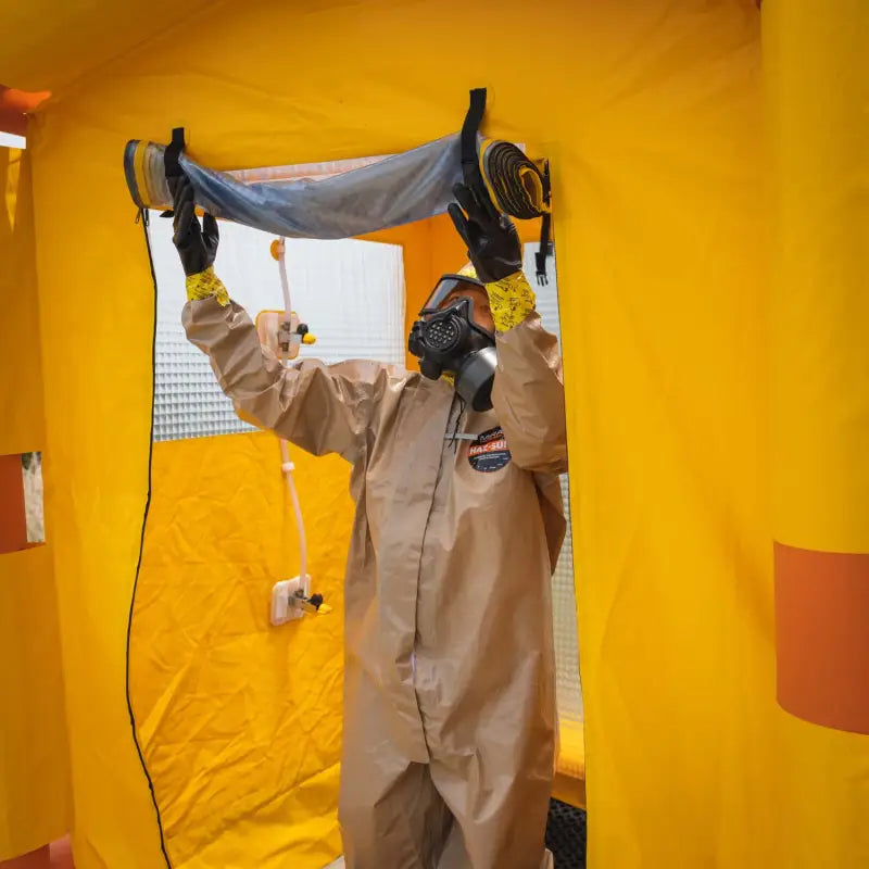 Worker in hazmat suit demonstrating the Mira Safety DS-1 portable decontamination shower